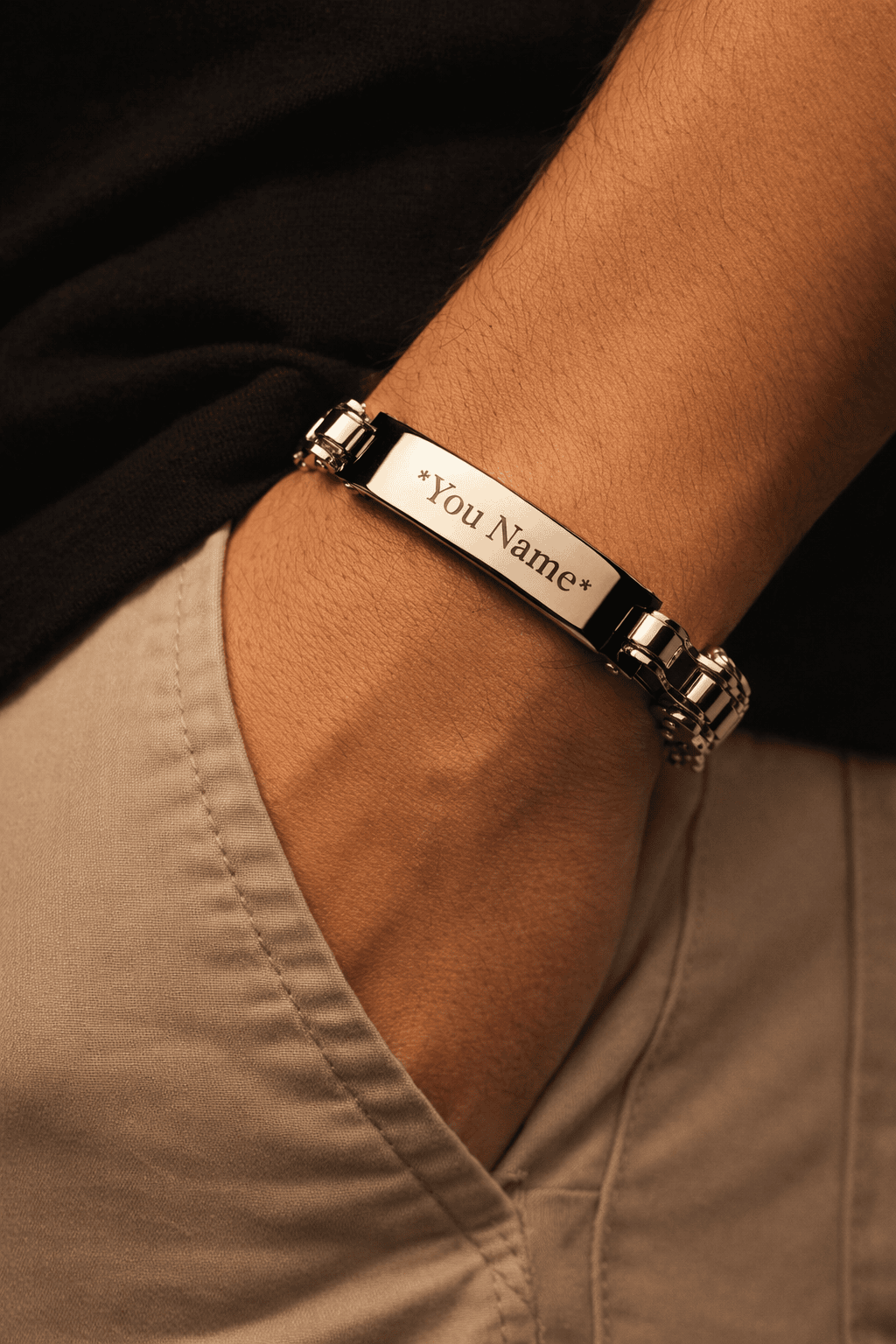 Close-up of a men's stainless steel custom name plate bracelet with engraved "Your Name" worn on wrist in pocket pose warm lighting Pakistan