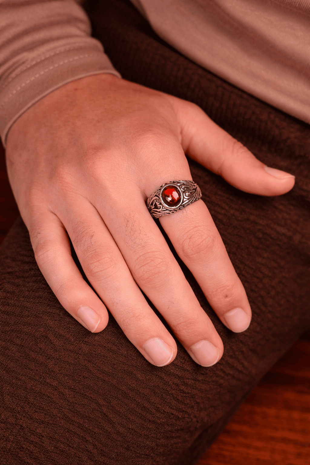 A man wearing a premium red Garnet stone ring with a silver-finish stainless steel band featuring intricate filigree patterns.