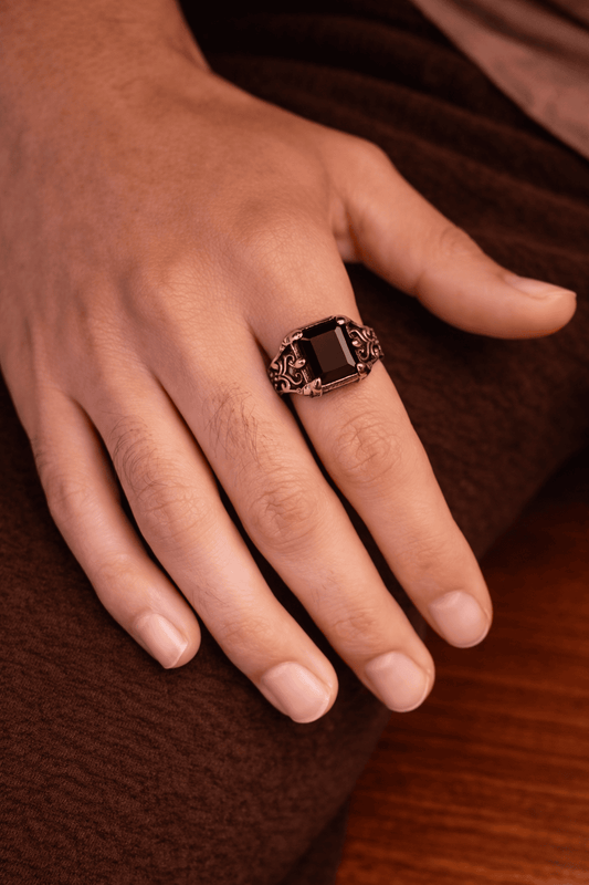A man wearing a Turkish style black Aqeeq stone ring with an intricate vintage silver-finish stainless steel band.