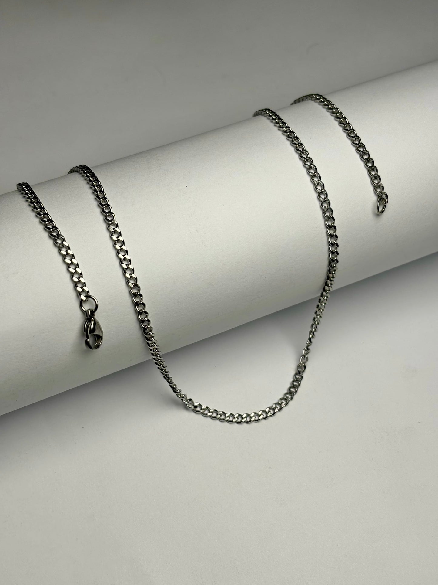 Stainless steel curb chain necklace for men Pakistan, polished silver flat curb link chain with lobster clasp on white background