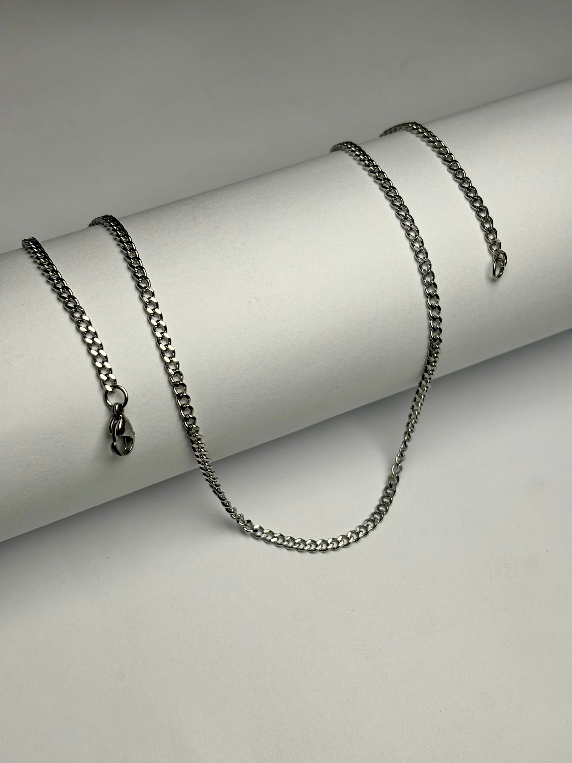 Stainless steel curb chain necklace for men Pakistan, polished silver flat curb link chain with lobster clasp on white background