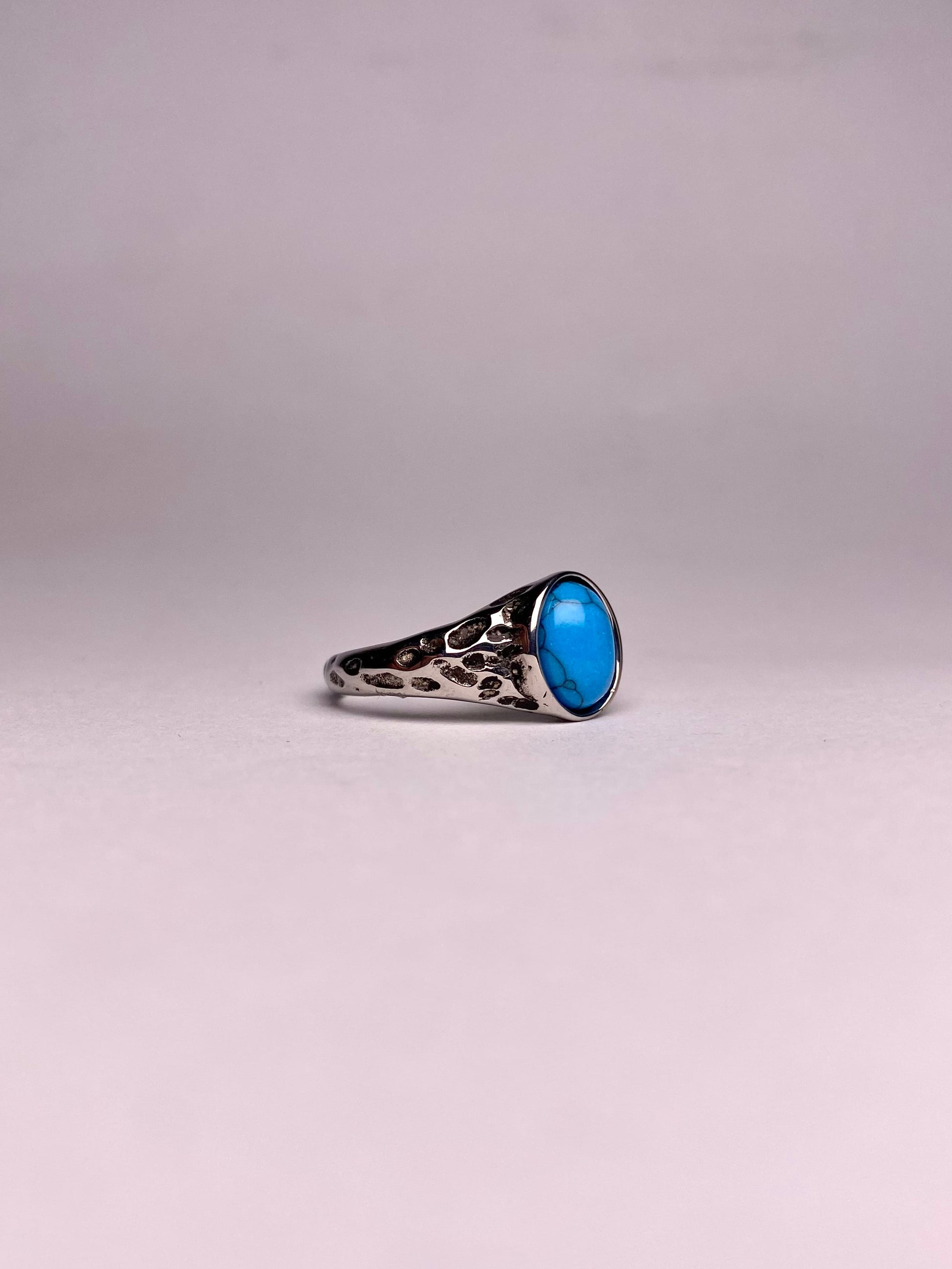 Side profile of a non-tarnish silver-tone stainless steel ring featuring a hammered texture and blue stone.