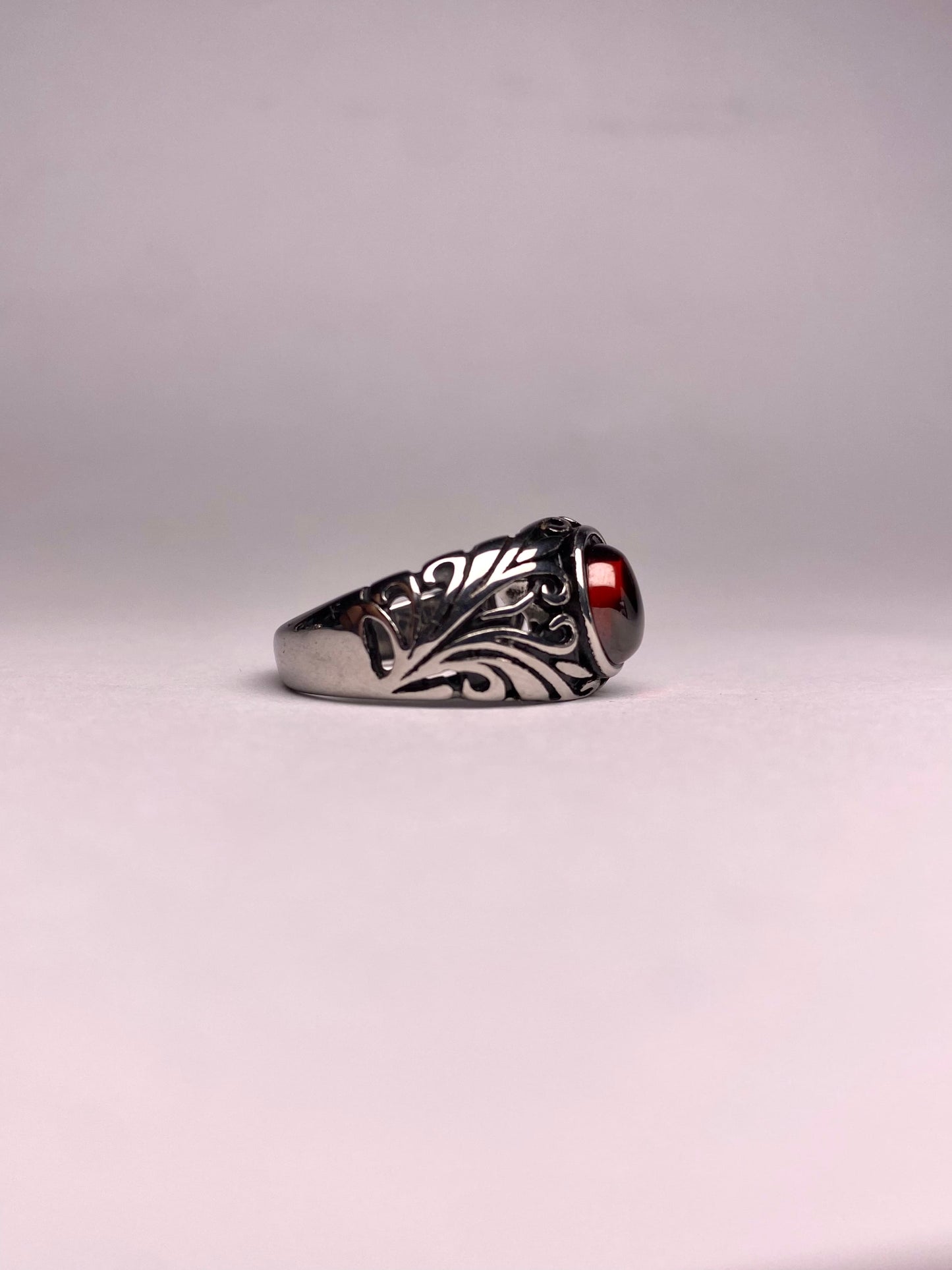 Side view of a Turkish-style Garnet ring showing the detailed leaf-pattern engraving on a non-tarnish steel band