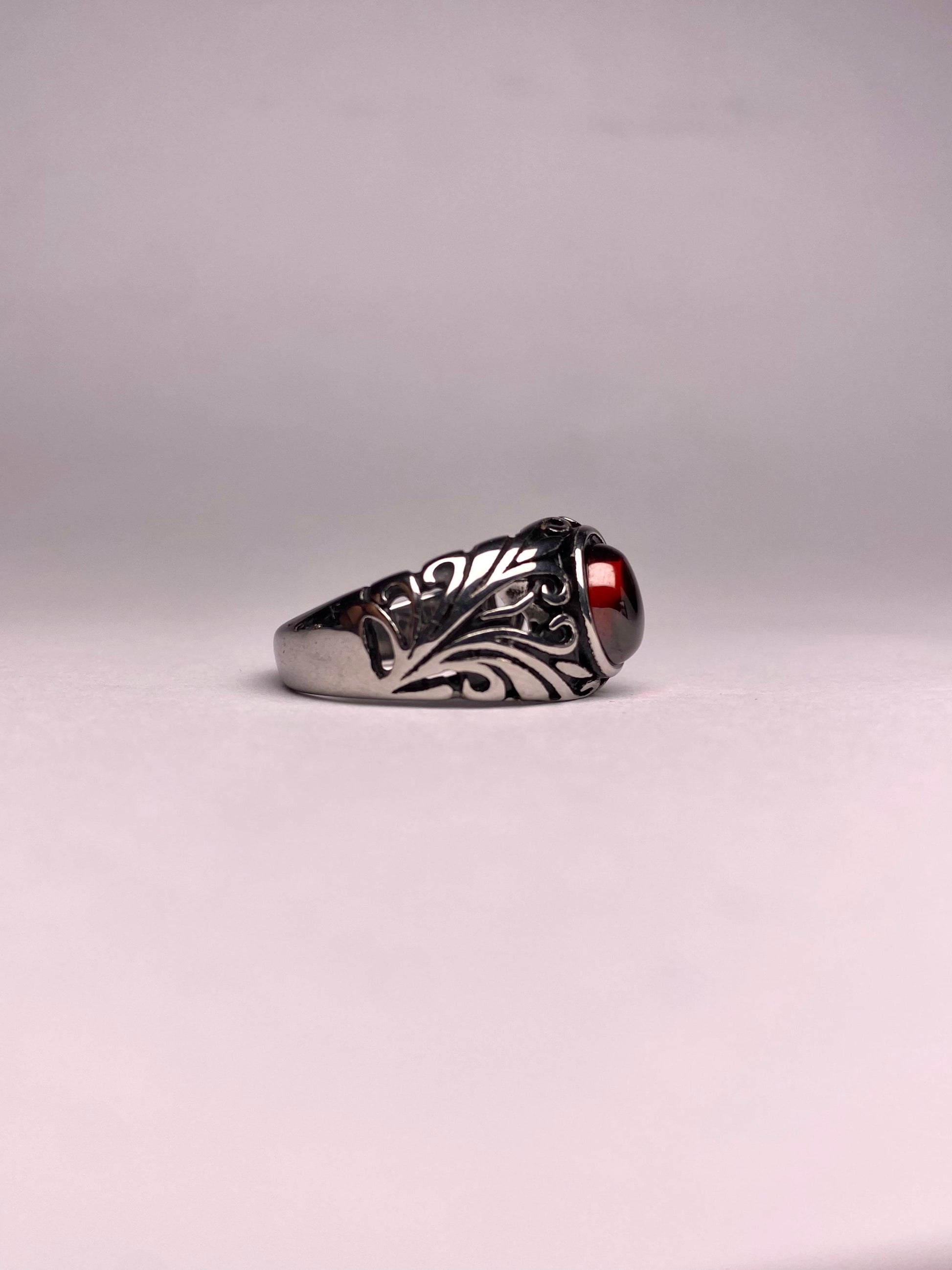 Side view of a Turkish-style Garnet ring showing the detailed leaf-pattern engraving on a non-tarnish steel band
